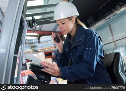 portrait of a woman driving forklift using walkie talkie