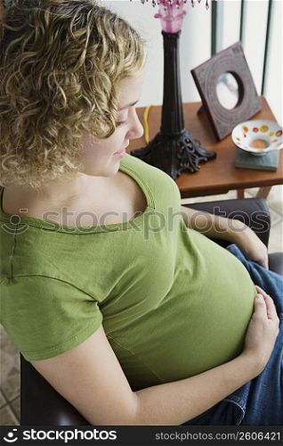 Portrait of a woman five months pregnant looking a belly