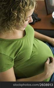 Portrait of a woman five months pregnant looking at belly