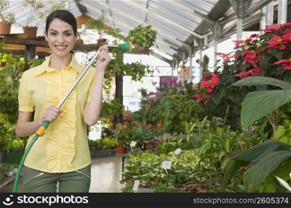 Portrait of a woman holding a hose in a garden center