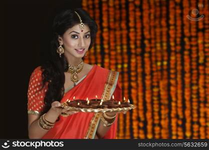 Portrait of a woman holding a tray of diyas