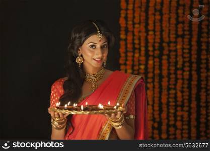 Portrait of a woman holding a tray of diyas