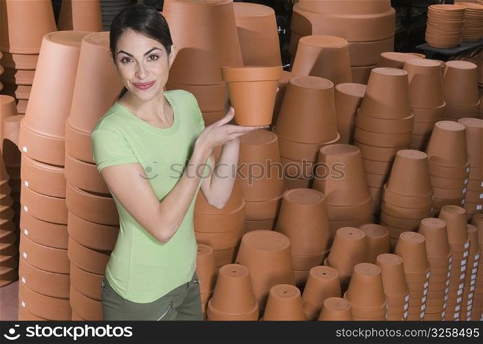 Portrait of a woman holding flower pot in a garden center