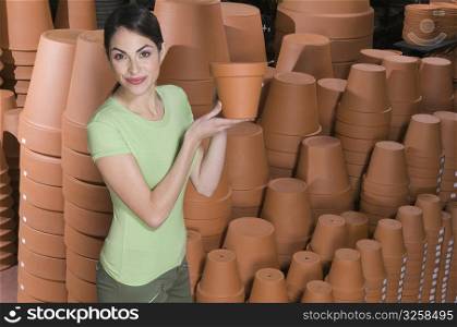 Portrait of a woman holding flower pot in a garden center