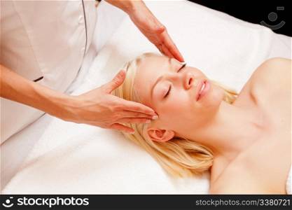 Portrait of a woman in a spa receiving a scalp massage