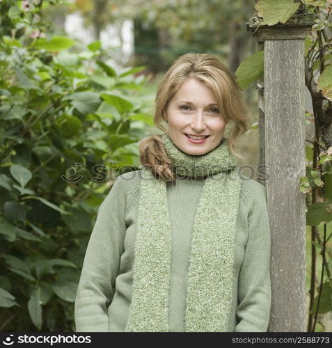 Portrait of a woman leaning against a pole and smiling