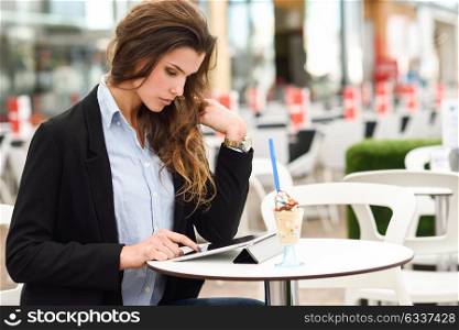 Portrait of a woman looking at her tablet computer, sitting in a coffee shop