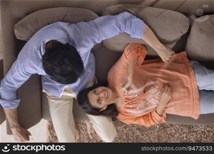 Portrait of a woman lying on her husband's lap while relaxing together on sofa