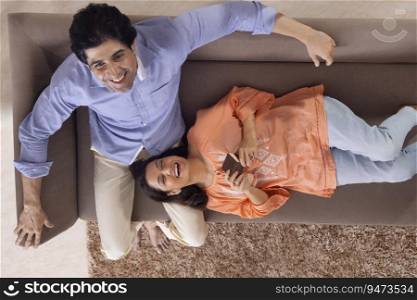 Portrait of a woman lying on her husband s lap while relaxing together on sofa