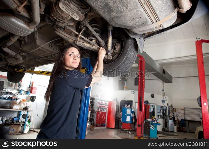 Portrait of a woman mechanic working on the underside of a car