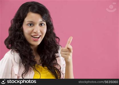 Portrait of a woman pointing finger over colored background