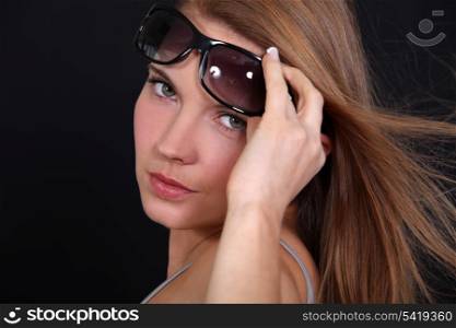 Portrait of a woman raising her sunglasses