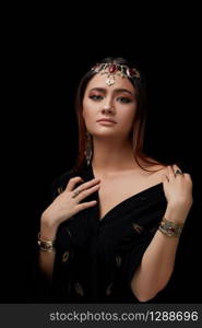 portrait of a woman&rsquo;s face, with Oriental-style jewelry on a black Studio background.