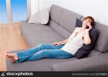 Portrait of a woman sitting on sofa, talking on phone
