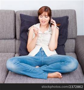 Portrait of a woman sitting on sofa, talking on phone