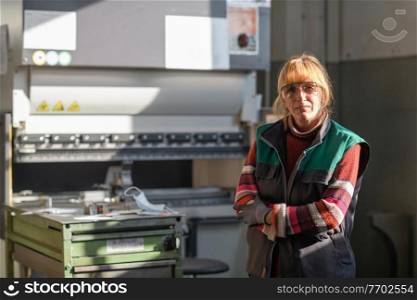 portrait of a woman standing in front of a CNC machine in goggles and working in a modern metal production and processing factory. High quality photo. portrait of a woman standing in front of a CNC machine in goggles and working in a modern metal production and processing factory