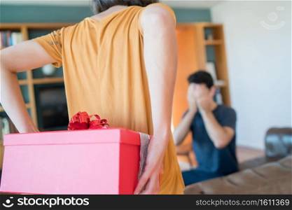 Portrait of a woman surprising her boyfriend with a present. Celebration and valentine’s day concept.. Woman surprising her boyfriend whith a present.