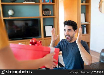 Portrait of a woman surprising her boyfriend with a present. Celebration and valentine&rsquo;s day concept.