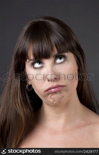 Portrait of a woman upset and thinking on something, against a grey background 