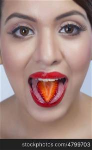 Portrait of a woman with a strawberry slice on her tongue