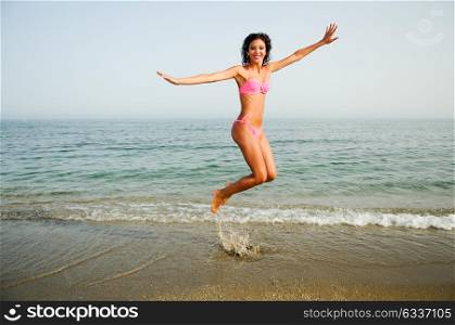 Portrait of a woman with beautiful body jumping in a tropical beach