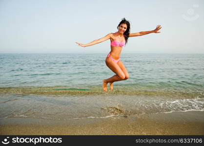 Portrait of a woman with beautiful body jumping in a tropical beach