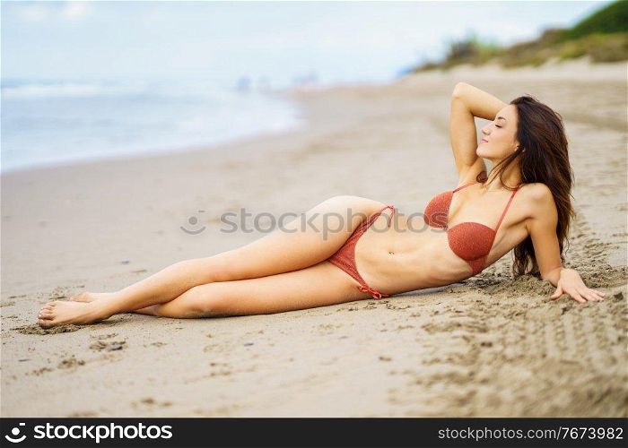 Portrait of a woman with beautiful body on a tropical beach wearing red bikini. Portrait of a woman with beautiful body on a tropical beach