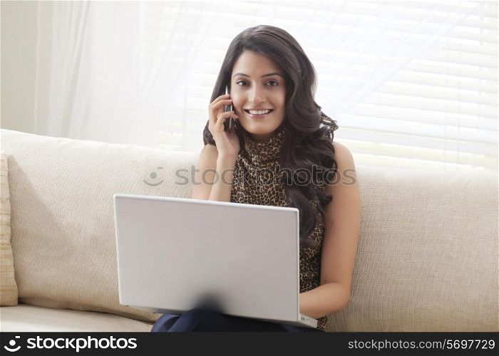Portrait of a woman with laptop talking on mobile phone