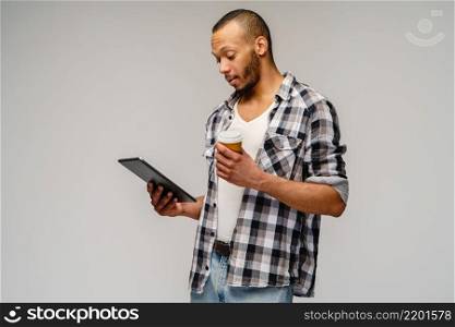 Portrait of a young african american man wearing casual shirt holding tablet pc pad and cup of coffee.. Portrait of a young african american man wearing casual shirt holding tablet pc pad and cup of coffee