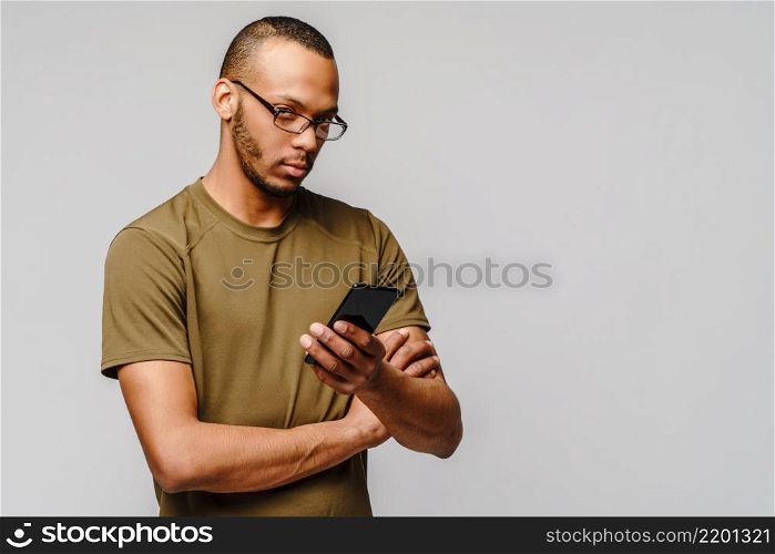 Portrait of a young african american man wearing glasses holding cell phone.. Portrait of a young african american man wearing glasses holding cell phone