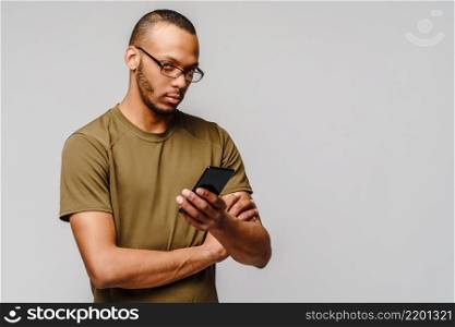 Portrait of a young african american man wearing glasses holding cell phone.. Portrait of a young african american man wearing glasses holding cell phone