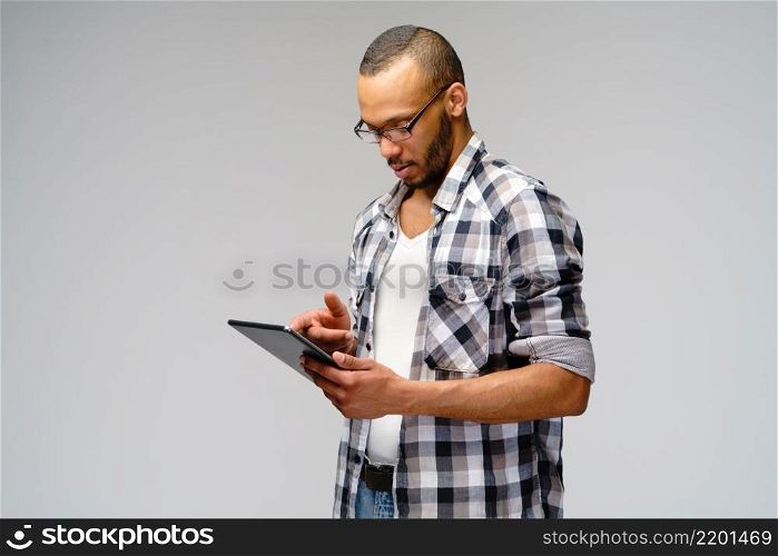 Portrait of a young african american man wearing green t-shirt holding tablet pc pad.. Portrait of a young african american man wearing green t-shirt holding tablet pc pad