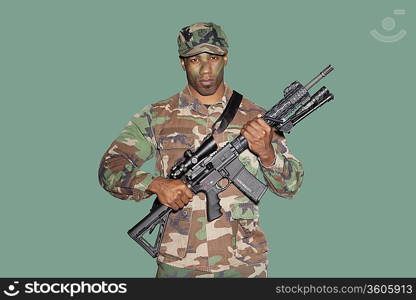 Portrait of a young African American US Marine Corps soldier with M4 assault rifle over green background