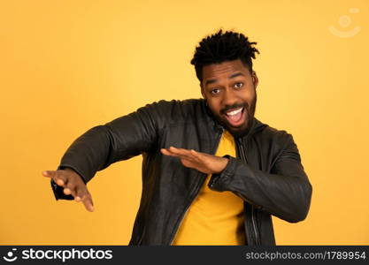 Portrait of a young afro man looking happy and excited while standing against isolated yellow background.