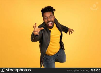Portrait of a young afro man smiling while trying to catch something with his hand against isolated background.