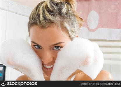 portrait of a young and cute girl in bathtub with face between foam