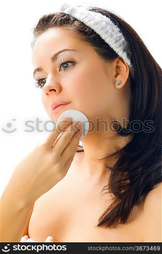 portrait of a young and pretty girl cleaning her face from make up using soft disk cleaner