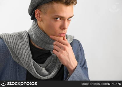 Portrait of a young artist wearing scarf and cap, against gray background