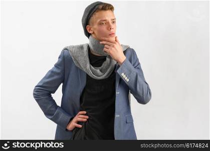 Portrait of a young artist wearing scarf and cap, against gray background
