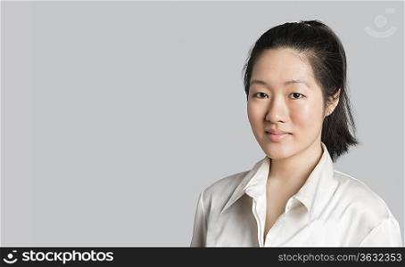 Portrait of a young Asian female doctor over gray background