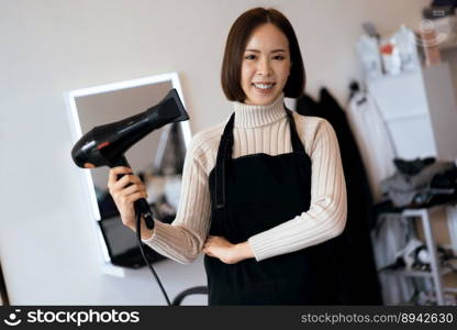 Portrait of a young asian female hairdresser holding qualified haircut tools in her salon for a woman’s haircut. Photo job concept for small business owner and haircare.. Portrait of a young asian female hairdresser holding qualified haircut tools.