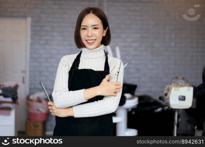 Portrait of a young asian female hairdresser holding qualified haircut tools in her salon for a woman’s haircut. Photo job concept for small business owner and haircare.. Portrait of a young asian female hairdresser holding qualified haircut tools.