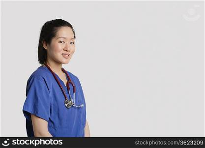 Portrait of a young Asian female surgeon smiling over gray background