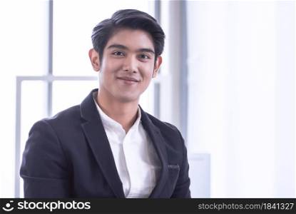 Portrait of a young asian handsome business man is standing in the office and smiling with confidence