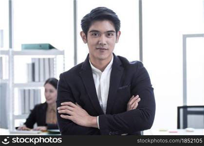 Portrait of a young asian handsome business man is standing in the office and smiling with confidence