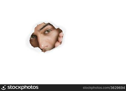 Portrait of a young Asian male peeking from paper hole
