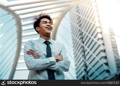 Portrait of a Young Asian Smiling Businessman in the City. Crossed Arms and looking away