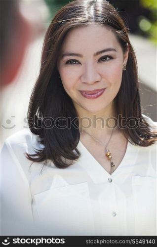 Portrait of a young Asian woman or businessowman smiling at a friend or colleague