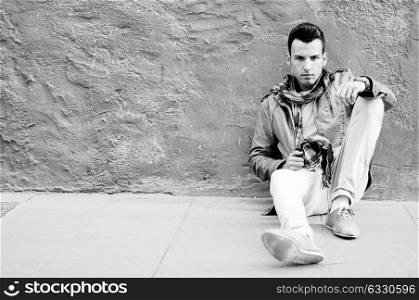 Portrait of a young attractive man sitting on the floor of the street