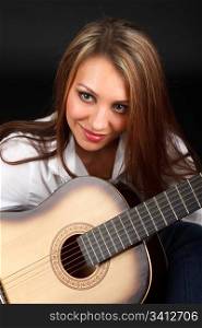 Portrait of a young attractive woman with a guitar on a black background